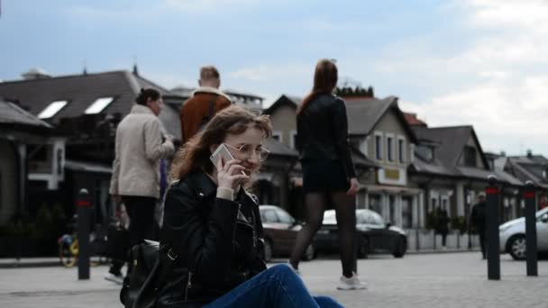 Студентська дівчина сидить на міській вулиці і розмовляє — стокове відео