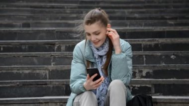 Hipster Kafkas Kız müzik dinliyor ve telefonda bir mesaj yazıyor.