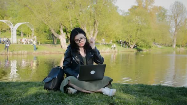 Chica programadora freelancer trabajando en un portátil en un parque de la ciudad — Vídeos de Stock