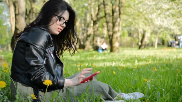 Joven mujer caucásica usando su teléfono inteligente en el parque — Vídeos de Stock