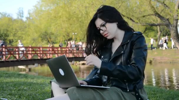 Mujer caucásica con computadora sentada cerca del lago de la ciudad — Vídeos de Stock