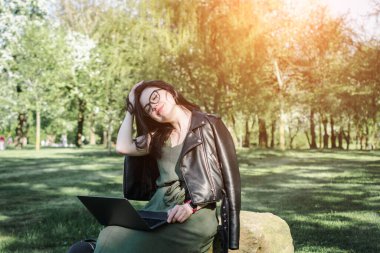 Yazın çimlerin üzerinde dizüstü bilgisayarı olan beyaz bir kız öğrenci.