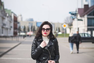 Güneşli bir bahar gününde, elinde telefonla caddede yürüyen güzel bir hippi kız.