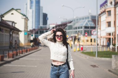 Güzel genç kız hippi kız ilkbaharda şehrinin caddesinde yürüyor.