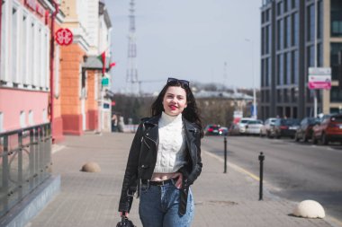 Güneşli bir günde, ilkbaharda güzel bir hippi kız şehrinin caddesinde yürür.