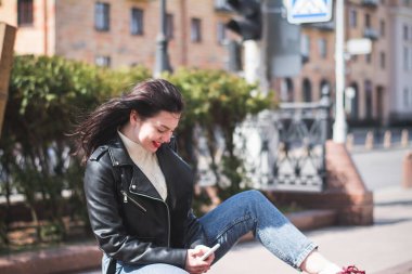 Genç, neşeli bir kadın cep telefonu ve mesaj kullanıyor. Şehir sokaklarında, yaşam tarzı konsepti.