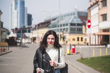 Şehrinin sokaklarında yürüyen güzel, genç, esmer bir hippi kız yürüyor ve seviniyor.