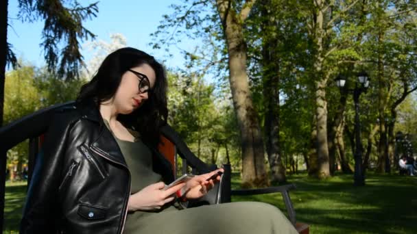 Retrato de una mujer feliz pagando en línea con tarjeta de crédito y teléfono inteligente en un parque de verano — Vídeos de Stock