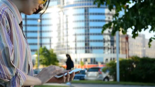 Young girl uses mobile on city street — Stock Video