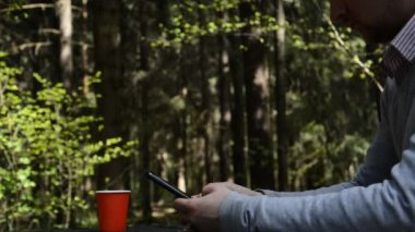 Ormanda akıllı cep telefonu kullanan bir adamın elleri.