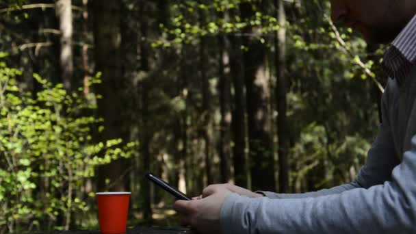 Egy férfi kezei, aki okos mobilt használ az erdőben. — Stock videók