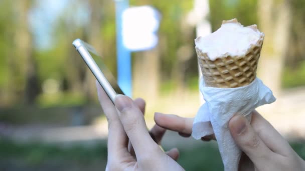 Chica con helado en sus manos escribe un mensaje en el teléfono — Vídeos de Stock