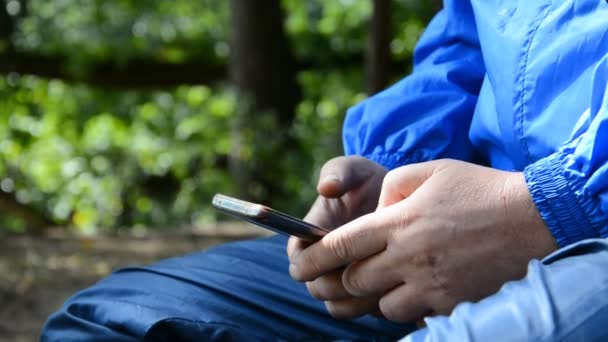 Caminante manos de un hombre usando un teléfono celular inteligente en el bosque, rodeado de naturaleza — Vídeos de Stock