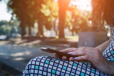 Gün batımında akıllı telefon kullanan kadın elleri.