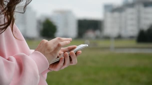 女性は夏の都市公園で携帯電話を使い — ストック動画