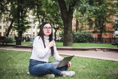 Kampüs şehrinde dizüstü bilgisayar kullanan güzel bir öğrenci.