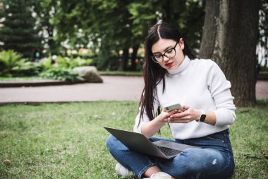 Kampüs şehrinde dizüstü bilgisayar kullanan güzel bir öğrenci.