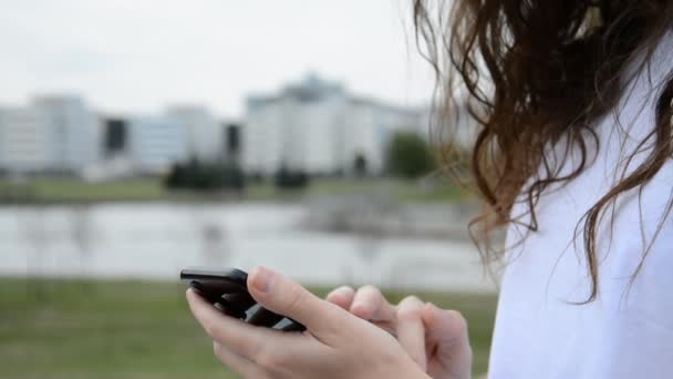 Primer plano de las manos femeninas usando un teléfono inteligente en un parque — Vídeos de Stock