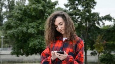 Kırmızı tişörtlü güzel kadın telefona bir mesaj yazıyor.