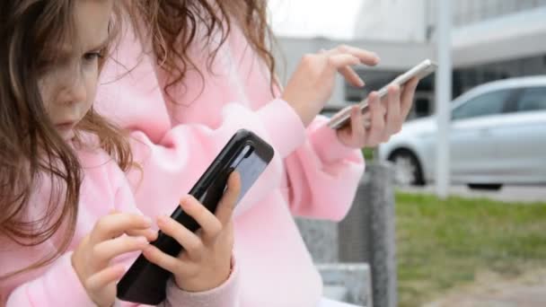 Fetiță cu un telefon în mâinile ei joacă un joc — Videoclip de stoc