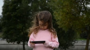 Küçük kız akıllı telefondan video izliyor.