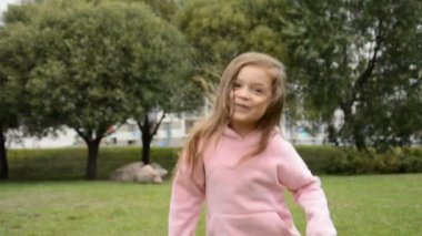 Mutlu küçük kız parkta zıplıyor ve seviniyor.