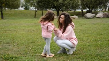 Mutlu anne ve küçük kız çimenlerde oynuyorlar.