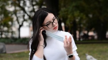 Gözlüklü esmer kız koruyucu bir maske takıyor.