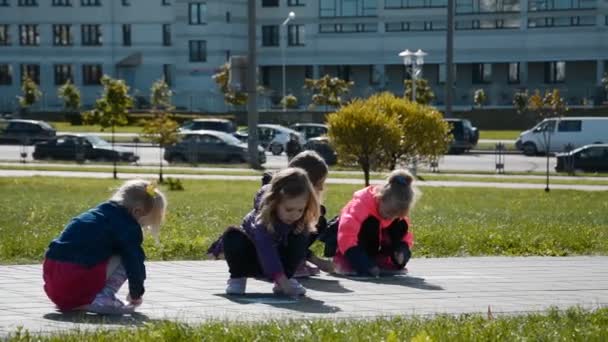 Vier kleine meisjes tekenen met krijtjes op het asfalt — Stockvideo