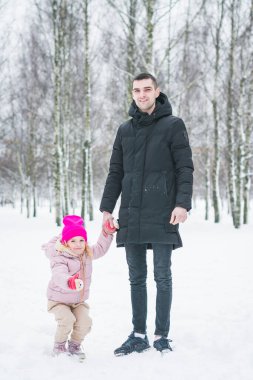 Güzel küçük kız babasıyla kış parkında oynuyor.