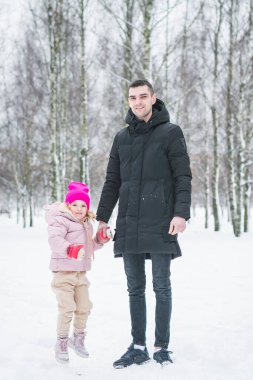 Güzel küçük kız babasıyla kış parkında oynuyor.