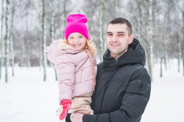 Güzel küçük kız babasıyla kış parkında oynuyor.