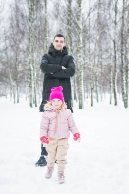 Güzel küçük kız babasıyla kış parkında oynuyor.