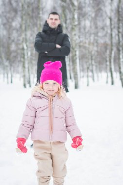Güzel küçük kız babasıyla kış parkında oynuyor.