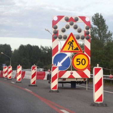 Banliyö karayolu çalışmaları, parlak yön sinyal ok işaretleri ve hız limiti olan mobil römork yaz gününde yolun sağ şeridinde 50 tabela ve yol işareti