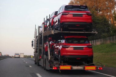 İki katlı taşıma kamyonu ve yarı karavan taşıma aracı banliyö otoyolu üzerinde kırmızı araçlar, yakın görüş, yeni Beyaz Rusya Çin arabaları ihracat lojistiği