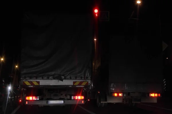 バックビューで乾燥アスファルトの夜の道路上の赤いトラフィックライトの背景にセミトレーラートラック 国際輸送物流 — ストック写真