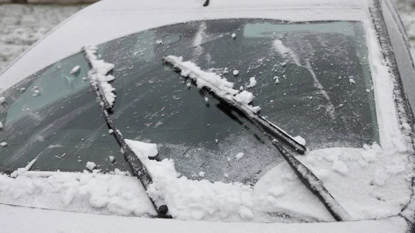 Wiper blades clean the car\'s windshield from snow close up, winter snowfal icing vehicle after snowstorm, safe winter driving, preparing for the trip