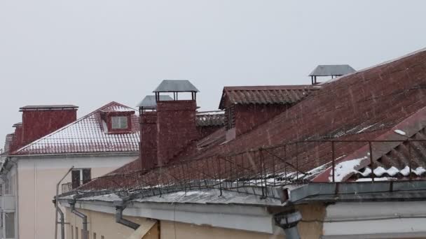 灰色の空の背景に雪のフレークとレンガのストーブと旧市街の家の赤いタイル張りの屋根 ヨーロッパの冬の雪 ヨーロッパの屋外冬の風景 — ストック動画