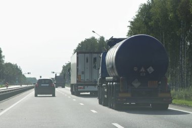 99 3257 ADR işareti olan yuvarlak bir tırı olan koyu mavi katran kamyon ve yaz günü bir köy yolunda hareket eden kamyonet, lojistik, sıcak sıvı madde yol taşımacılığı