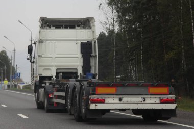 Yaz günü banliyöde asfaltlanmış otoyolda beyaz, boş kamyonet konteynır taşımacılığı. Arka manzara. Uluslararası lojistik, kargo taşımacılığı, taşımacılık endüstrisi.
