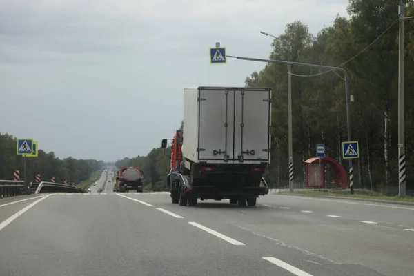 郊外の高速道路 リアサイドワイドビュー 配送自動車物流 自動車輸送上のボードドライブ上の壊れたトラックと車のキャリアトラック — ストック写真