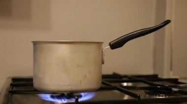Paslanmaz çelik mutfak gaz ocağında eski bir tava. Turuncu büyük alevler yanıp sönüyor. Kapalı alanda yangın önleyici.