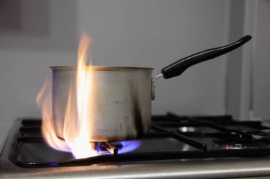 Alüminyum eski tava paslanmaz çelik mutfak gaz ocağı, yüksek mavi turuncu alev flaşı, kapalı alanda pişirme güvenlik yangın kodu.