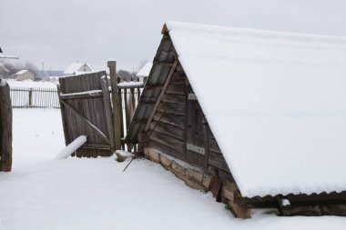 Kış günü, Rusya 'nın kışlık köy manzarasında, ahır karla kaplı, eski kırsal bir kulübede yıpranmış ahşap bir arka plan.