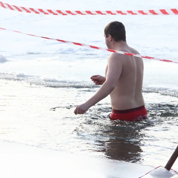 冬季运动 一个俄罗斯男子穿着泳裤在寒冷的冬日里 在冰洞里游泳 健康的生活方式 — 图库照片