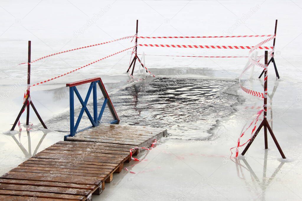 Empty ice hole with wooden planked pathway boardwalk and fence on a Sunny frosty winter day, winter ice swimming sport healthy lifestyle