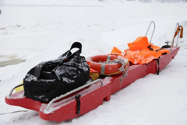 Rode Noodsledeboot Met Oranje Veiligheidsjassen Reddingsring Witte Sneeuwachtergrond Bevroren Winterdag — Stockfoto