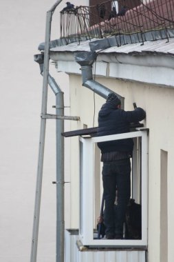 Slav işçiler çok katlı eski bir binanın en üst katındaki balkona çatı döşüyorlar.