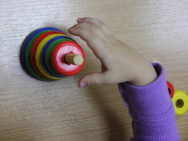 Çocukların renkli ahşap piramit kule mantık oyuncağı. Beyaz bir çocuğun elinde daire şeklinde. Yaratıcılığın erken gelişimi.